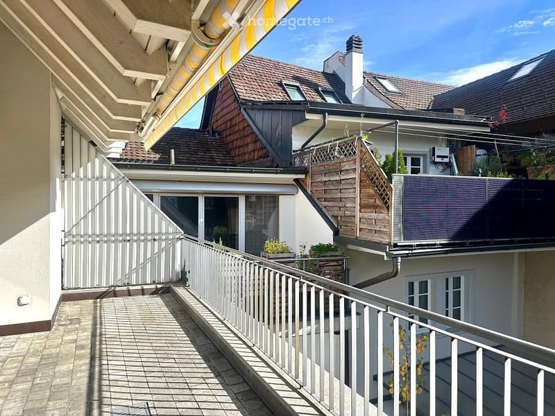 Exterior shot of a building with tiled terrace, balcony with metal railings, and solar panels