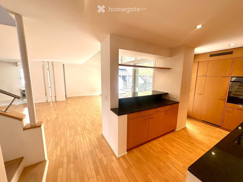 empty room with wooden floors, large window, wooden counter, wooden cabinets, black countertop