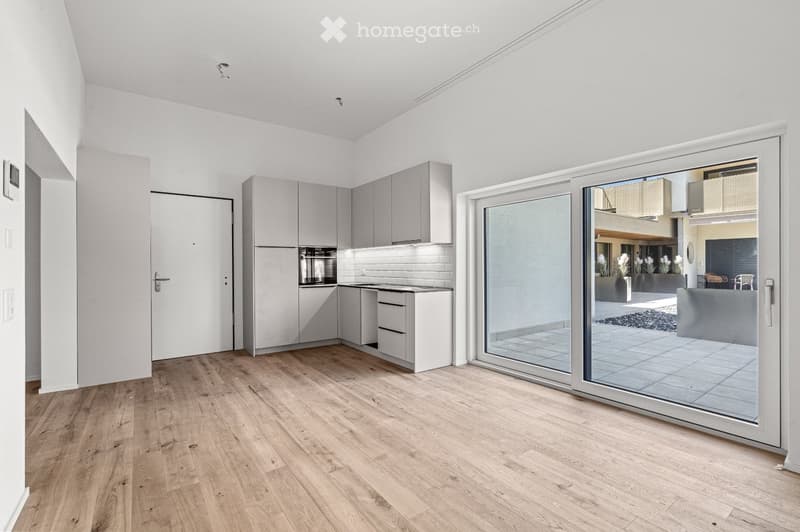 Modern kitchen with grey cabinets, white brick backsplash, and a large sliding glass door leading to an outdoor area.