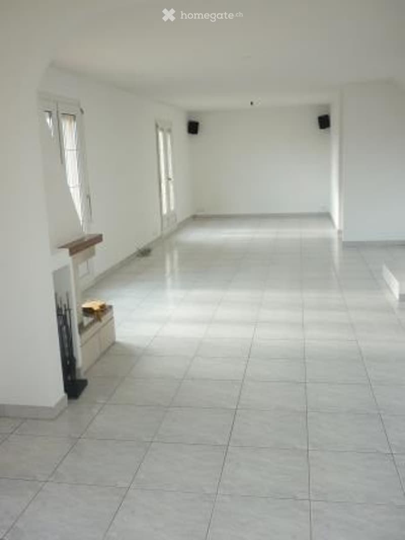 Empty room with white walls, tiled floor, and large windows. No furniture or equipment present.