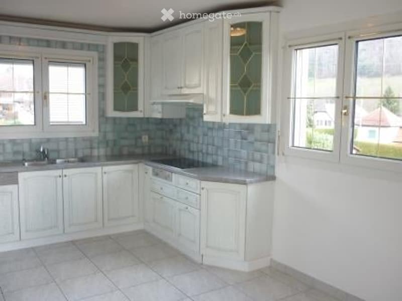 Bright kitchen with white cabinets, stainless steel sink, dishwasher, and tiled backsplash.