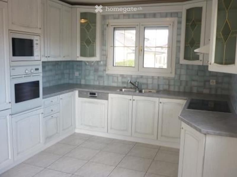 Bright kitchen with white cabinets, stainless steel appliances, and a tiled backsplash.