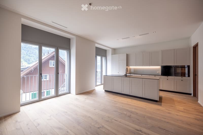 Modern kitchen with white cabinets, a central island, and large windows offering a scenic view of the surrounding landscape.