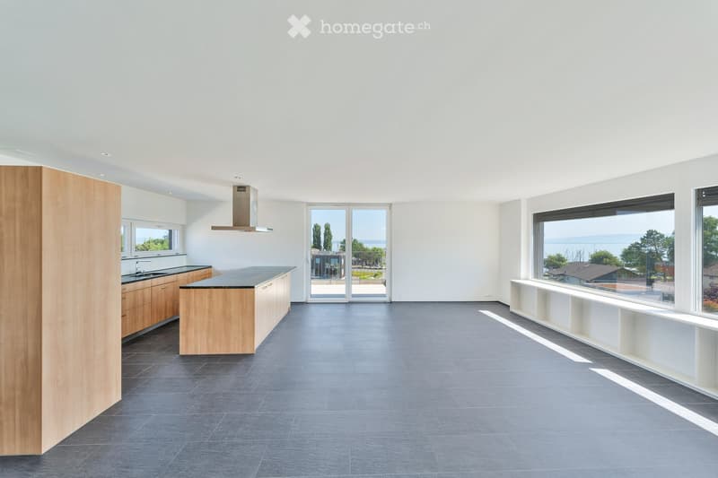Modern kitchen with light wooden cabinets, a central island, and large windows overlooking a scenic view.