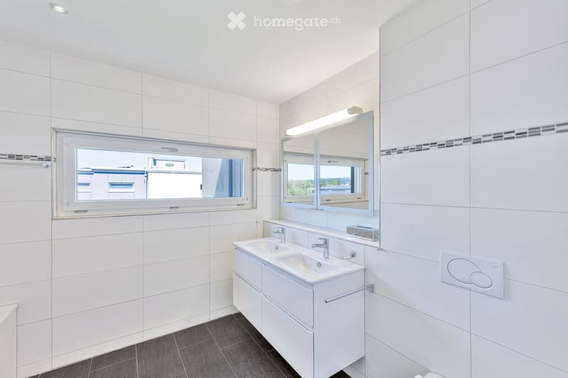Modern bathroom with white tiles, double sink, large mirror, and built-in cabinets.