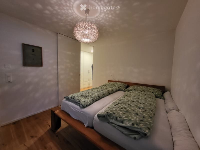 two beds, green sheets, wooden bed, white walls, wooden floor, decorative lamp