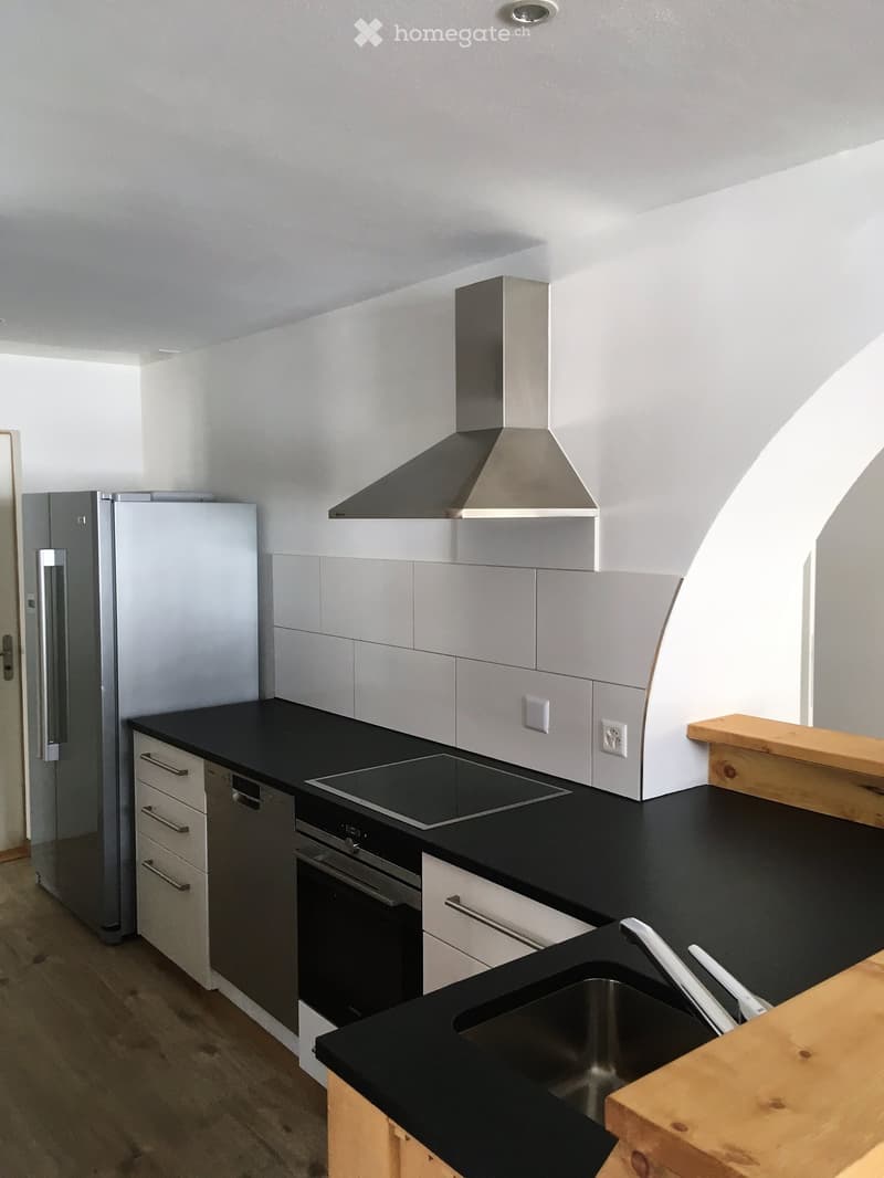 Modern kitchen with black countertops, stainless steel appliances, and white cabinets.