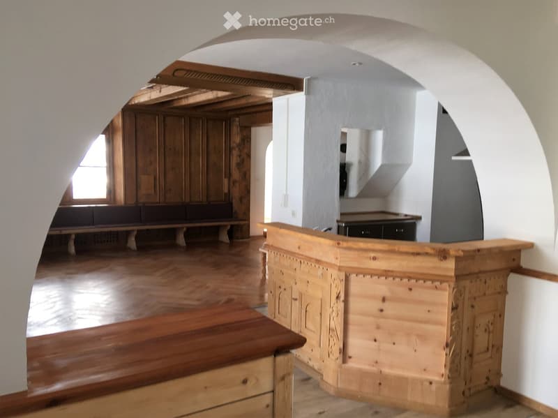Wooden bench, counter, and cabinet in a spacious room with wooden flooring and arched ceiling.