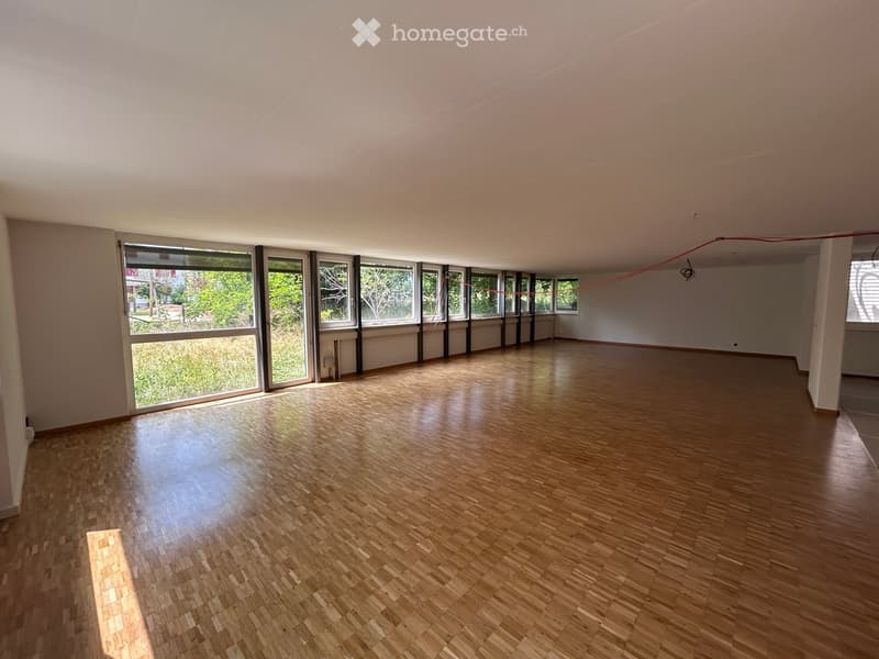 Empty room with wooden flooring and large windows, no furniture or equipment present.