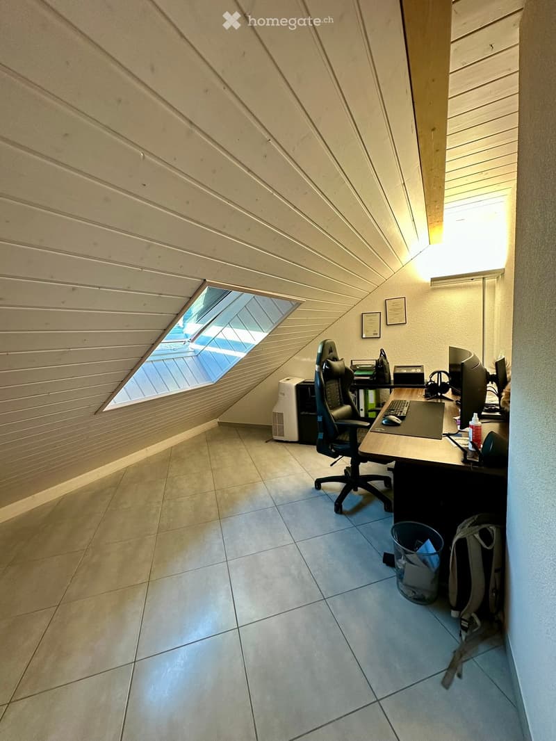 Office space with a desk, chair, computer, and air conditioner, featuring a skylight window and tiled floor.