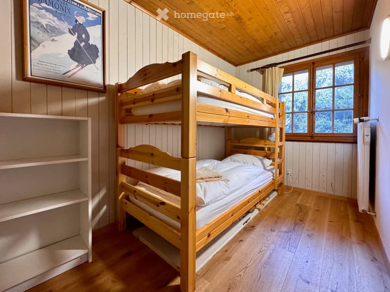 Cozy wooden bedroom with a bunk bed, shelves, and a framed poster on the wall.