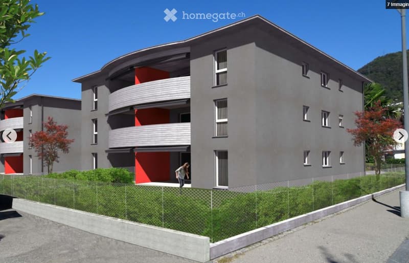 Modern multi-story residential building with grey facade, red accents, balconies, and surrounding greenery.