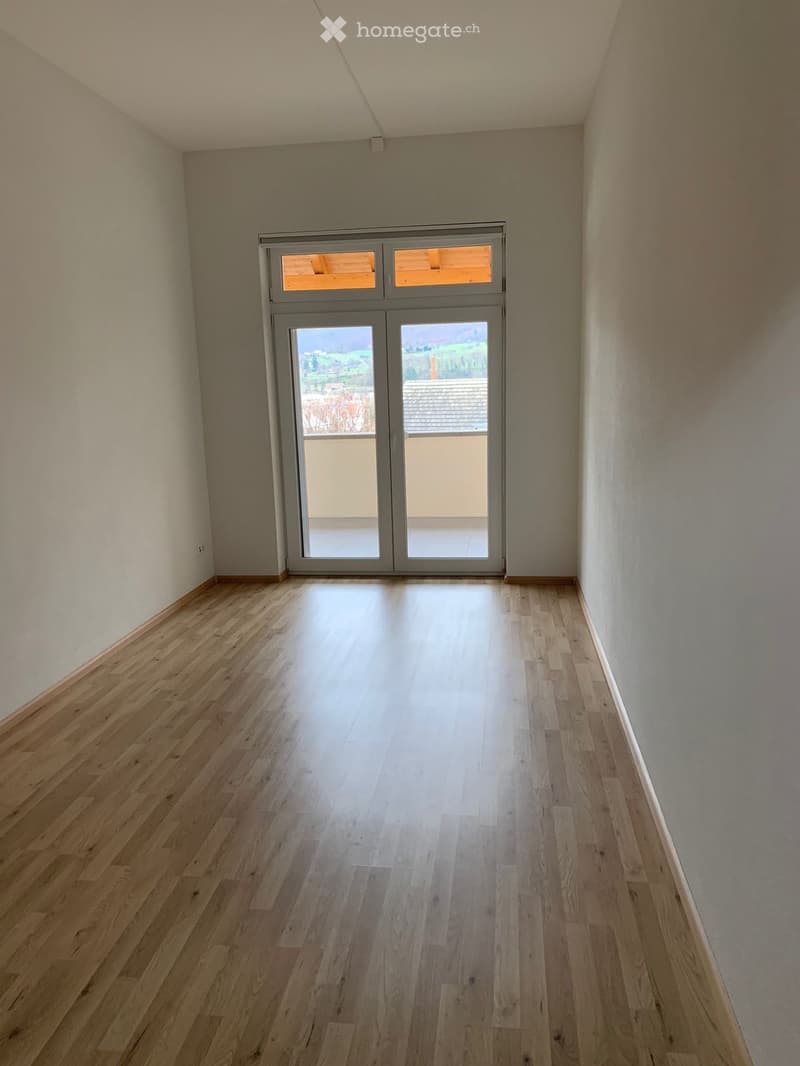 Empty room with wooden flooring and large sliding glass doors leading to a balcony or outdoor area.