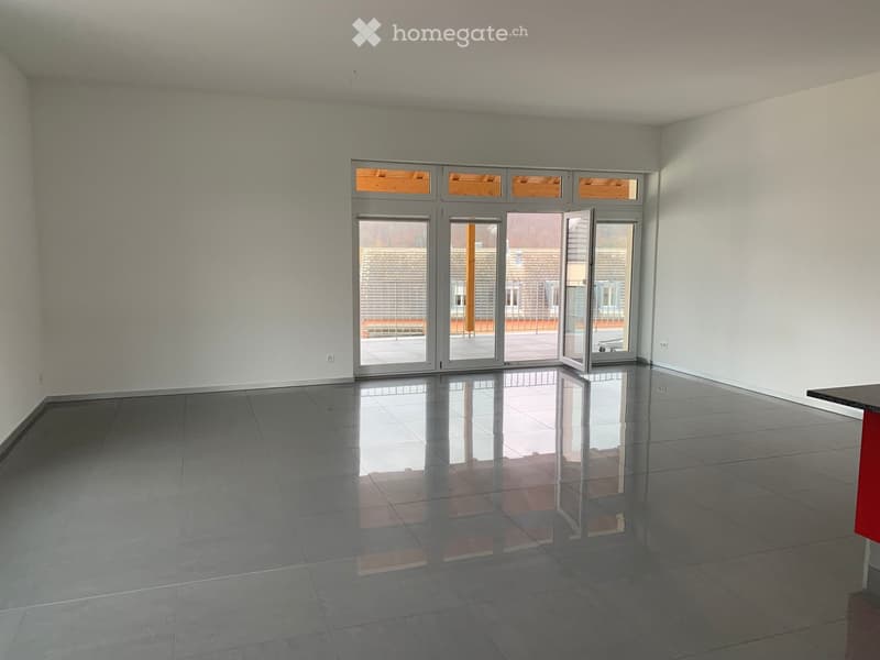 Empty room with grey tiled floor, white walls, and large glass sliding doors leading to a balcony.