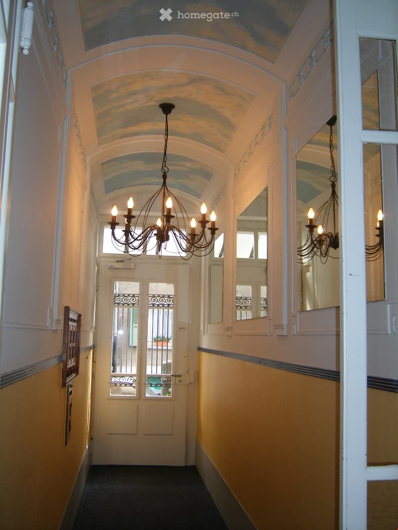 Elegant hallway with arched ceilings, ornate chandeliers, and decorative mirrors on the walls.