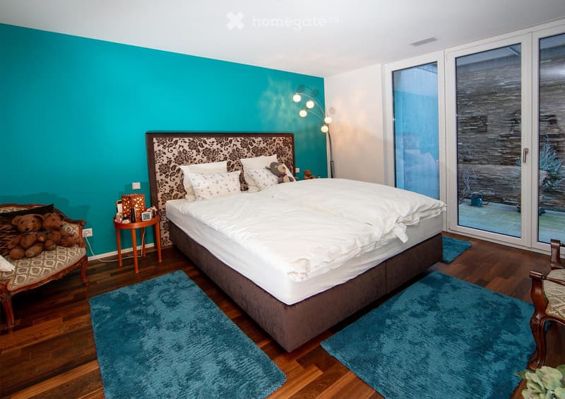 Cozy bedroom with a large bed, nightstand, armchair, floor lamp, and decorative rug.