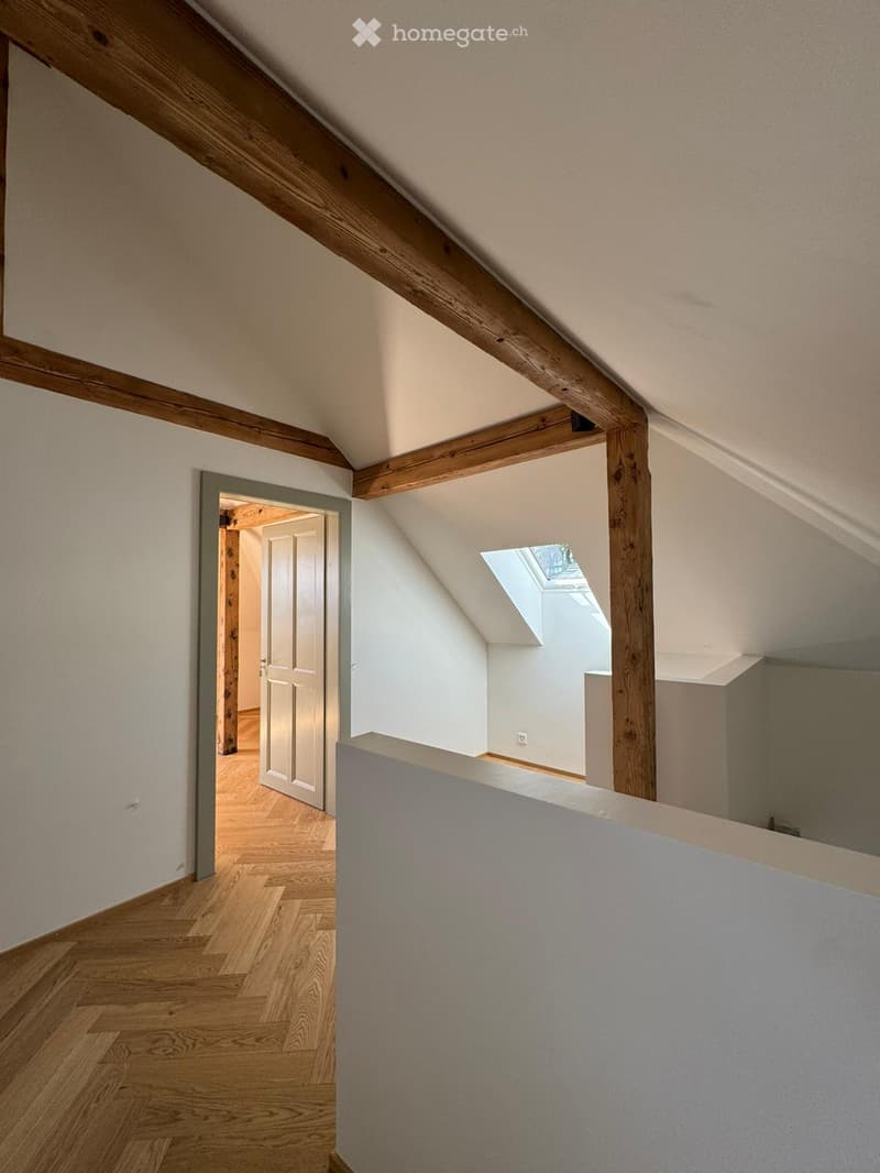 wooden beams, wooden parquet, small window, sloped ceiling, white walls, empty door