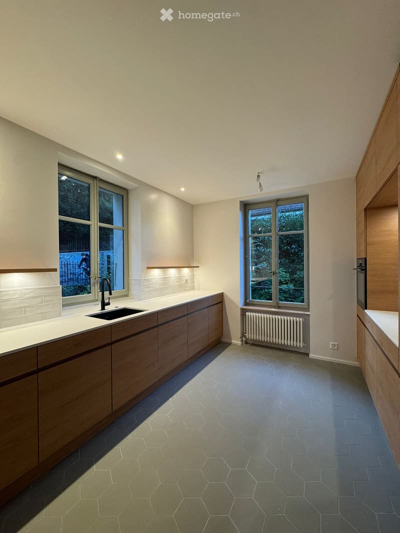 modern kitchen with white cabinets, black sink, wooden floor, radiator, windows