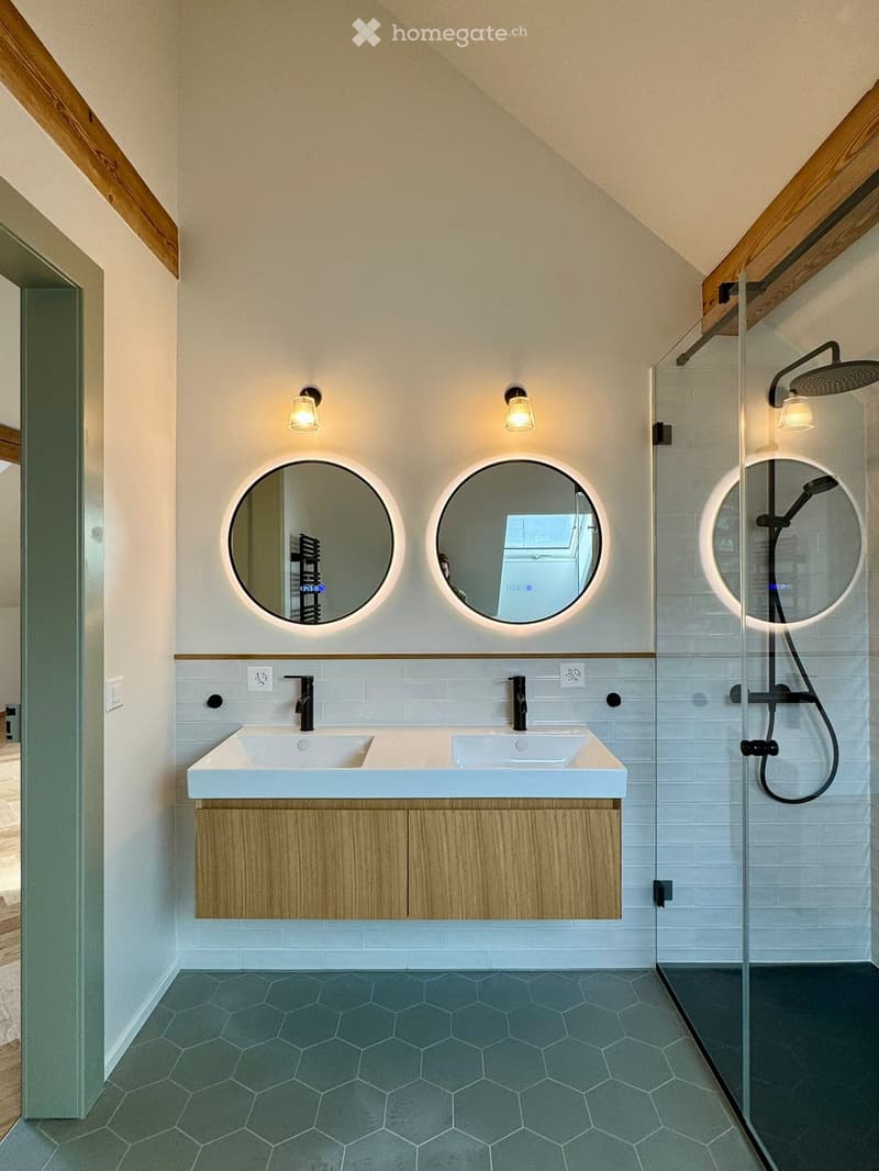 modern bathroom with hexagonal tiles, double sinks, round mirrors, glass shower enclosure, ceiling lights