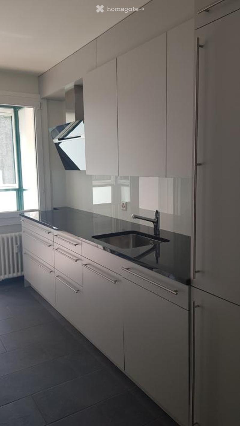 Modern kitchen with white cabinets, black countertops, and a stainless steel sink and faucet.