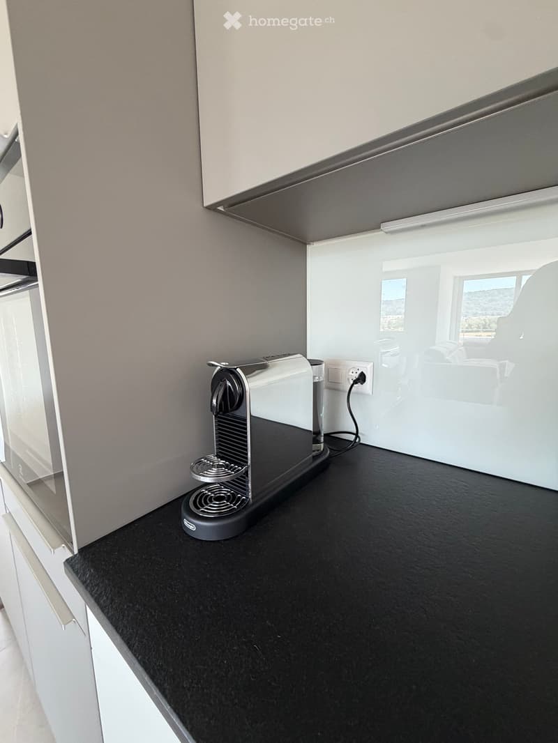 Modern kitchen with black countertop, white cabinets, and a coffee machine on the counter.