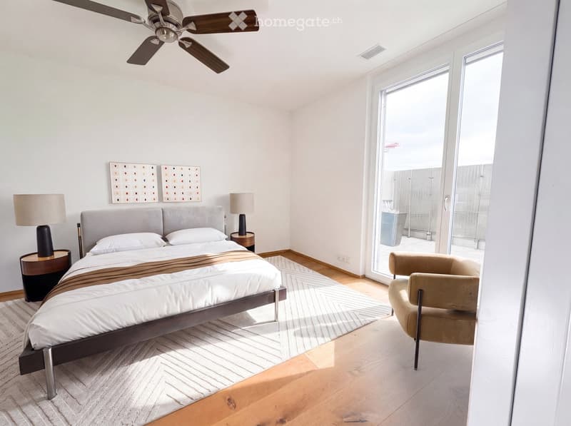 Modern bedroom with a large bed, nightstands, lamps, a chair, and a ceiling fan. Large sliding glass doors lead to a balcony.