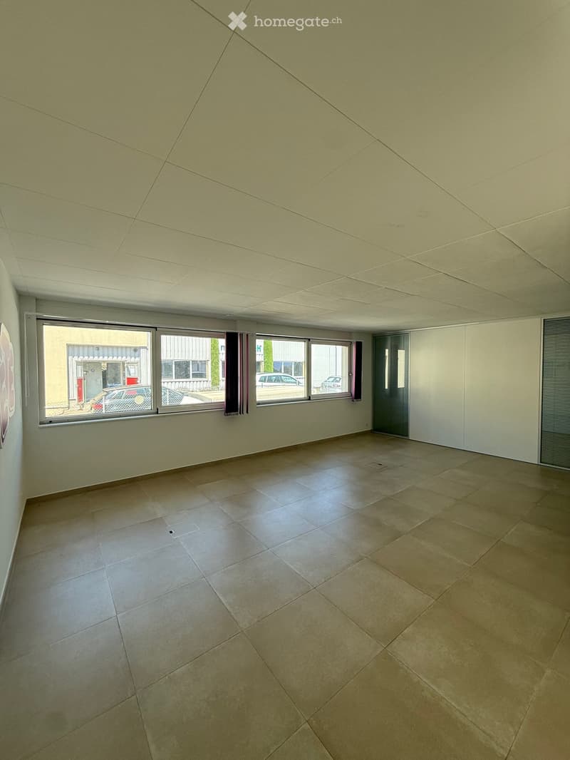 Empty room with tiled floor, large windows, and white walls.