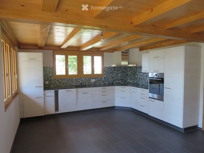 Modern kitchen with white cabinets, dark tiled floor, stainless steel appliances, and a mosaic backsplash.
