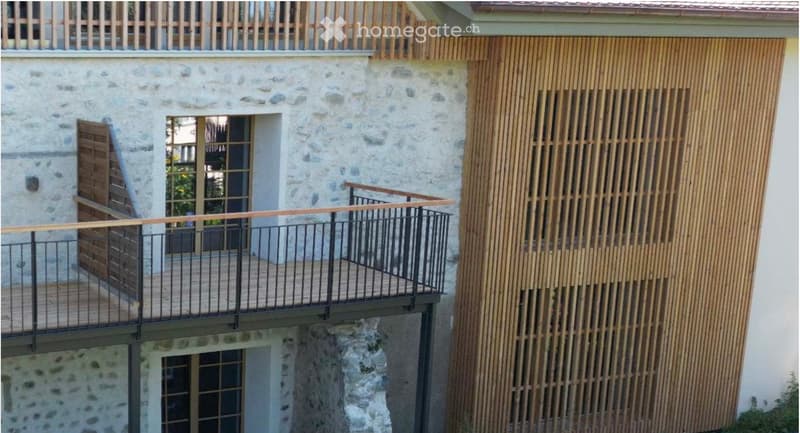 Balcony with wooden decking, metal railing, and wooden lattice screen on the adjacent wall.