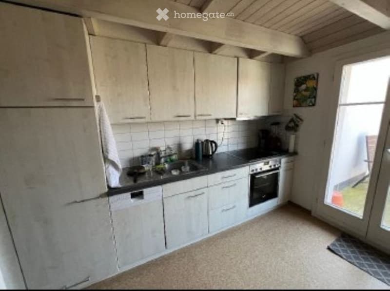 Modern kitchen with white cabinets, stainless steel appliances, and a black countertop. Features include a refrigerator, sink, oven, dishwasher, and a coffee maker on the counter.
