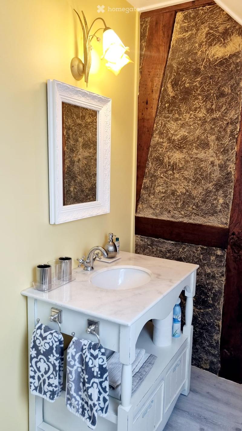 Bathroom with a white vanity, marble countertop, sink, mirror, and decorative towels.