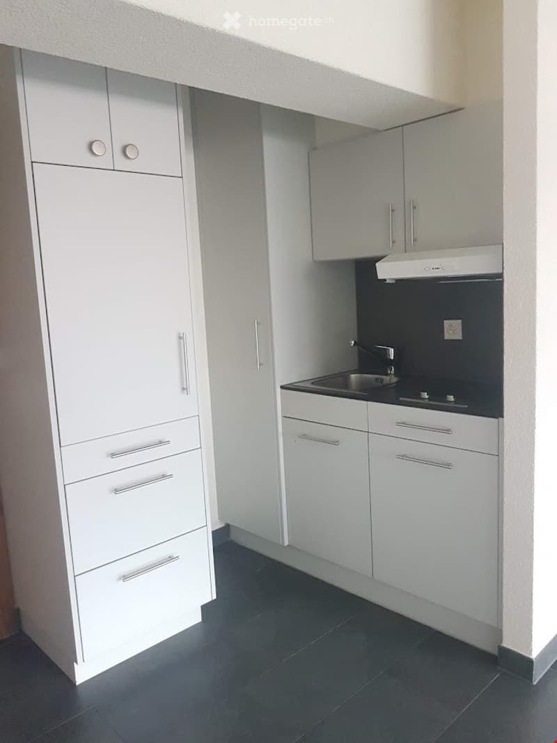 Kitchen: white cabinets, tiled floors, black countertop, stainless steel sink, electric hob, extractor hood, built-in dishwasher, small refrigerator