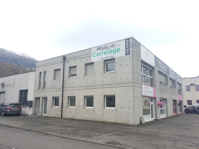 2 story building, gray walls, rectangular windows, signboard, car parked outside