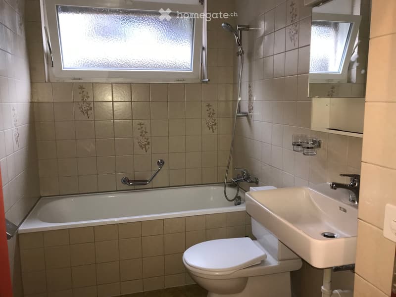 Bathroom with a bathtub, toilet, sink, shower, and a small window for natural light.
