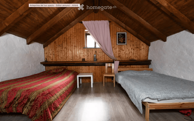 Cozy attic bedroom with wooden walls and slanted ceilings, featuring two single beds, a small table, and a chair.