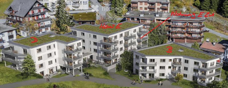 Aerial view of a modern residential complex with multiple buildings, green roofs, balconies, and surrounding greenery.