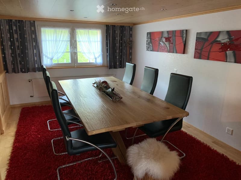 Dining room with a wooden dining table, black chairs, red shag rug, and modern artwork on the wall.