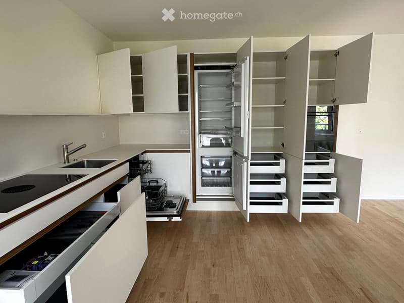 Modern kitchen with white cabinets, open shelving, stainless steel appliances, and wooden flooring.