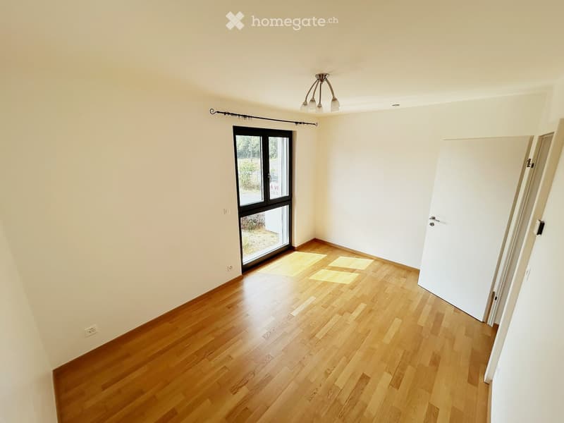 Empty room with wooden flooring, white walls, and a large glass door leading outside. No furniture or equipment is present.