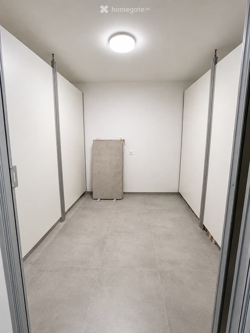 Empty hallway with tiled floor, white walls, and a single round ceiling light fixture.