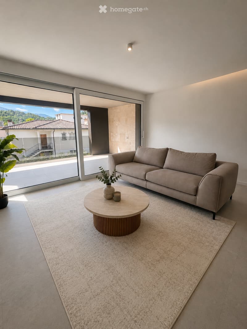 Modern living room with a beige sofa, round wooden coffee table, small vase with plant, and a large window offering a scenic view.