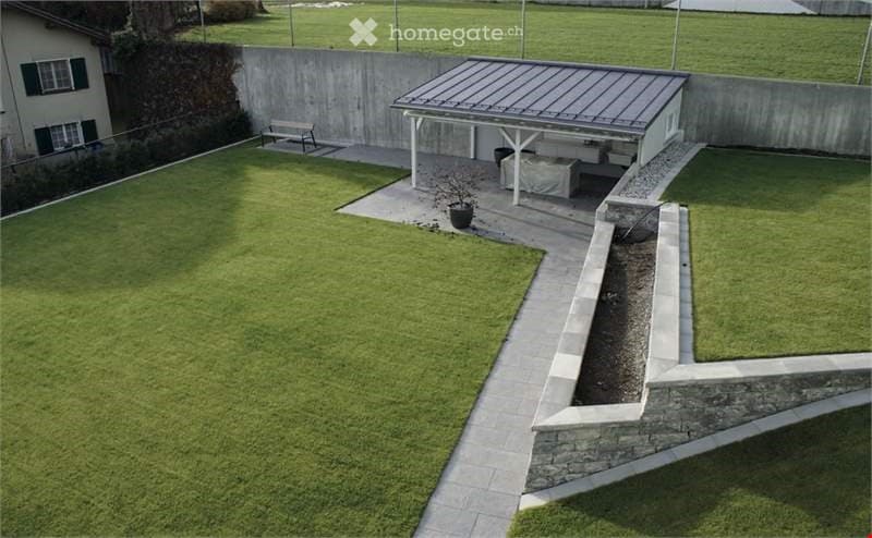 backyard with green lawn, stone paths, wooden bench, metal pergola, grassy lawn