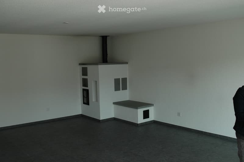 Empty room with white walls, dark tiled floor, and a small built-in bench with a window opening above it.