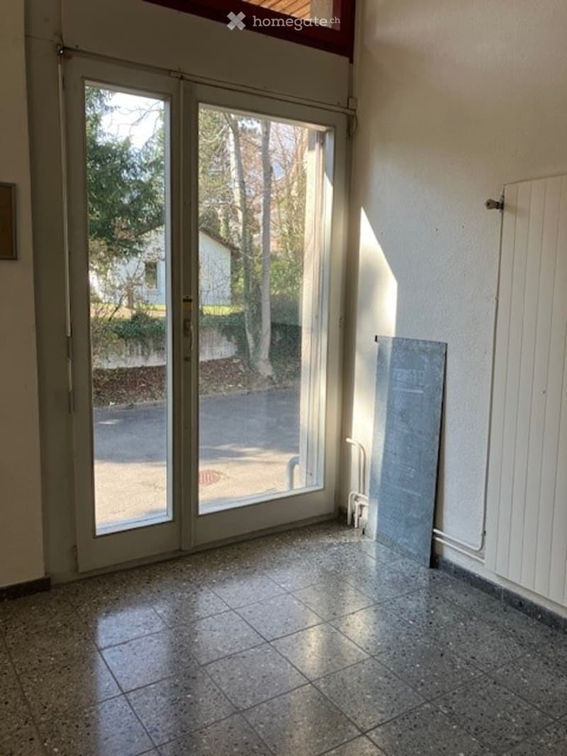 Empty room with sliding glass doors, tiled floor, white walls, and a radiator on the right side.