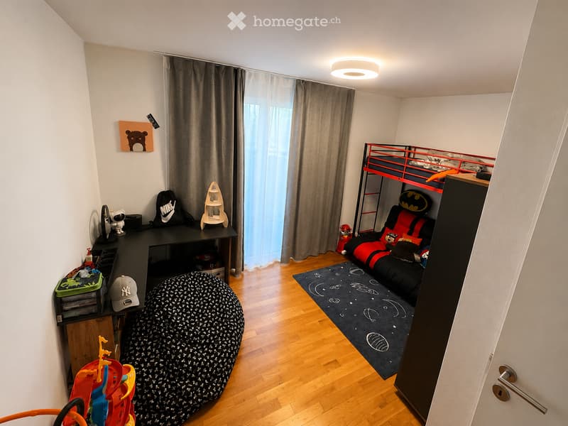 A cozy, well-lit bedroom with a bunk bed, desk, bean bag chair, and various toys and decorations.