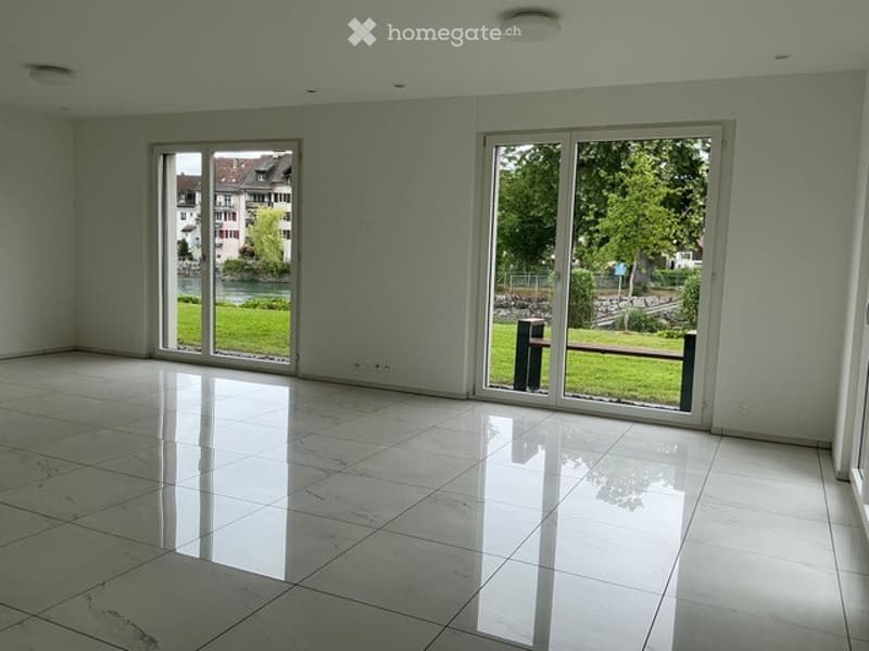 Completely empty room with large windows, white tiled floor, and natural light. No furniture or equipment.