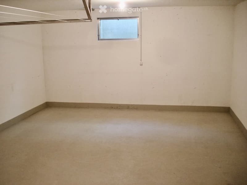 Empty room with concrete floor, white walls, and a small window with blinds. No furniture or equipment present.
