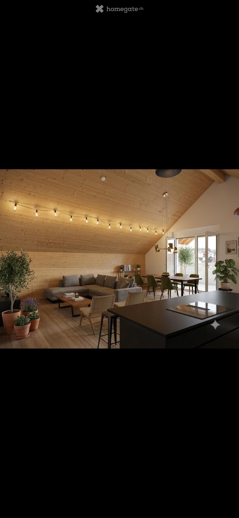 Open-concept living and dining area with a modern aesthetic. Features a grey sectional sofa, coffee table, dining table with chairs, kitchen island, and several potted plants. The space has wooden walls and ceiling with string lights.