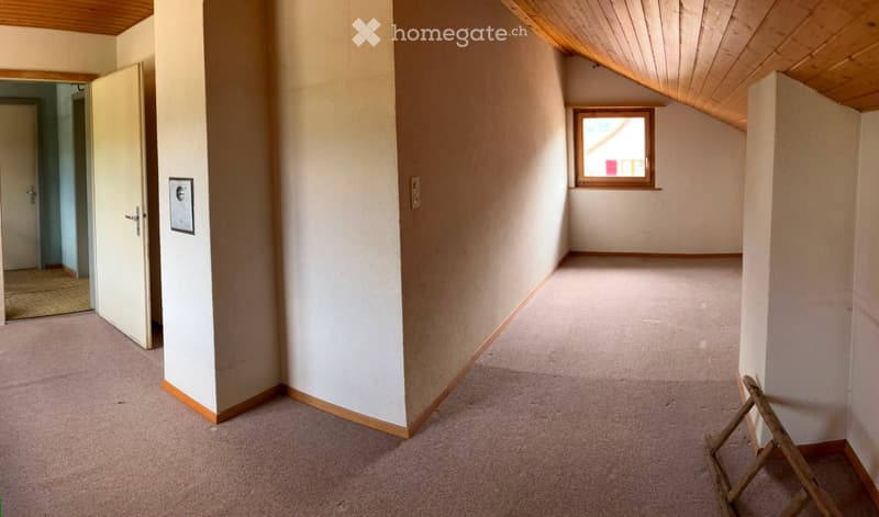 Empty hallway with beige carpeting, white walls, wooden trim, and a small window at the end. A door is open to another room on the left.