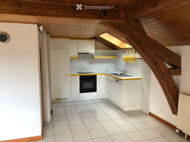 Compact kitchen with white cabinets, stainless steel appliances, and a wooden staircase leading to an attic space.